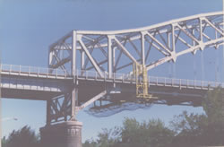 Suspended Work Platform Rolls Along Top of Exterior Sidewalk on an Overhead Truss Type Bridge