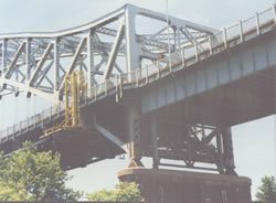 Suspended Work Platform Rolls Along Top of Exterior Sidewalk on an Overhead Truss Type Bridge