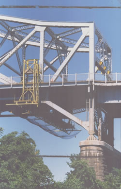 Suspended Work Platform Rolls Along Top of Exterior Sidewalk on an Overhead Truss Type Bridge