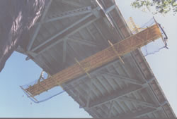 Suspended Work Platform Rolls Along Top of Exterior Sidewalk on an Overhead Truss Type Bridge